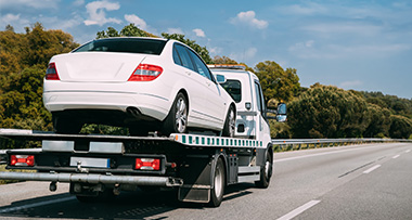 a white car being transported on top of a tow truck